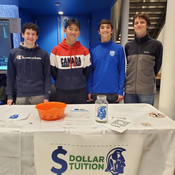 Dollar Tuition Club founders Max, Matteo, Zhenghang, and Ian standing behind their fundraising table at Stoneham High School